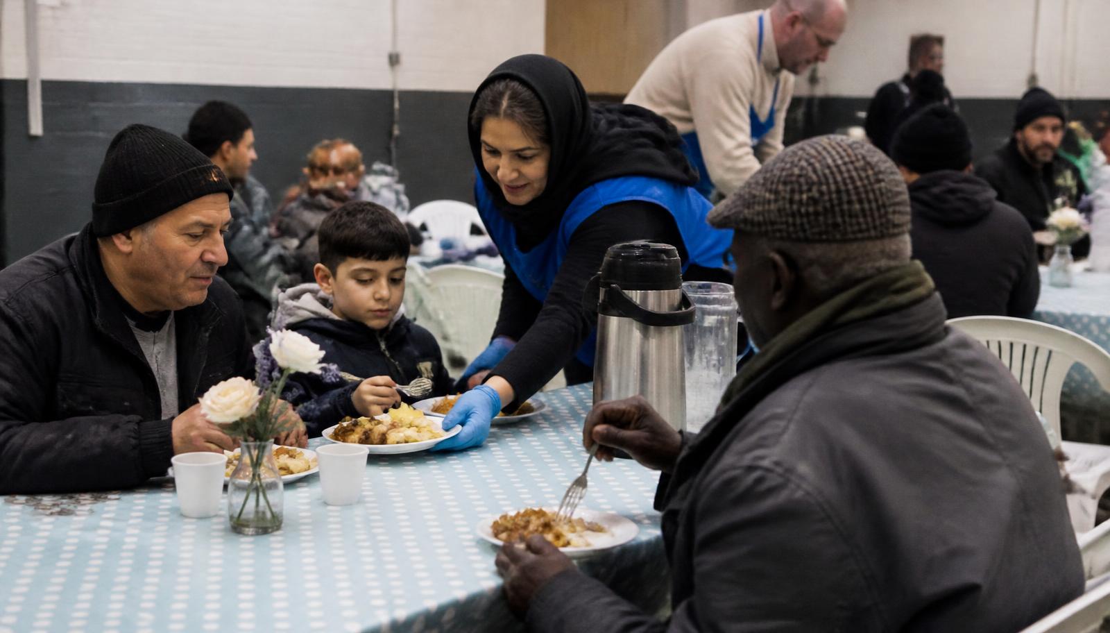 A small community group sharing a meal together at a wooden table